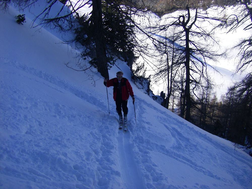 Steile Spitzkehren durch den schütteren Wald oberhalb der Rinne